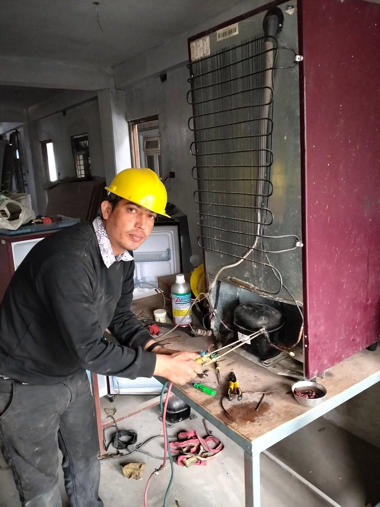 Technician recharging refrigerant gas on a refrigerator