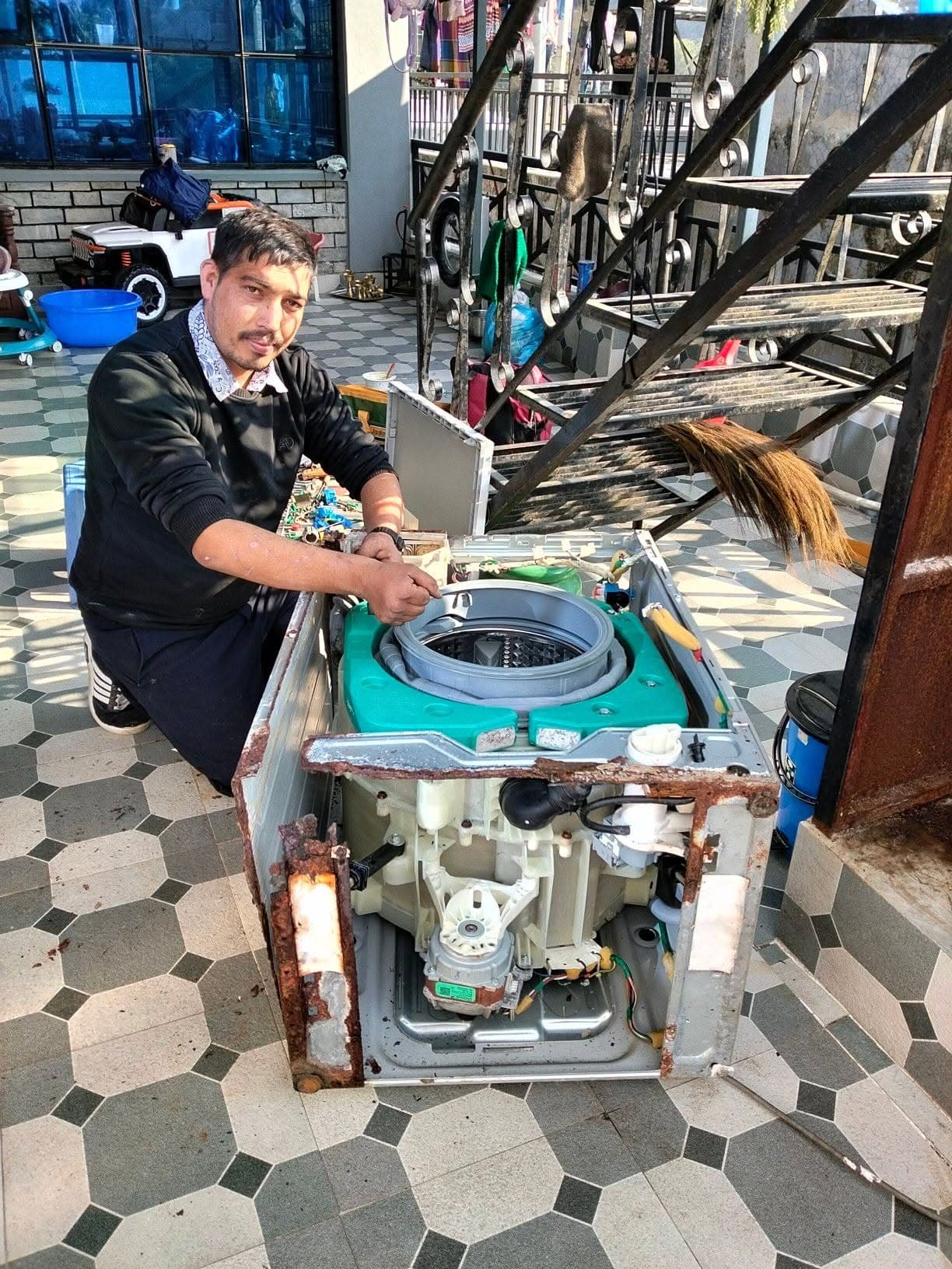 Technician welding a washing machine frame during repair
